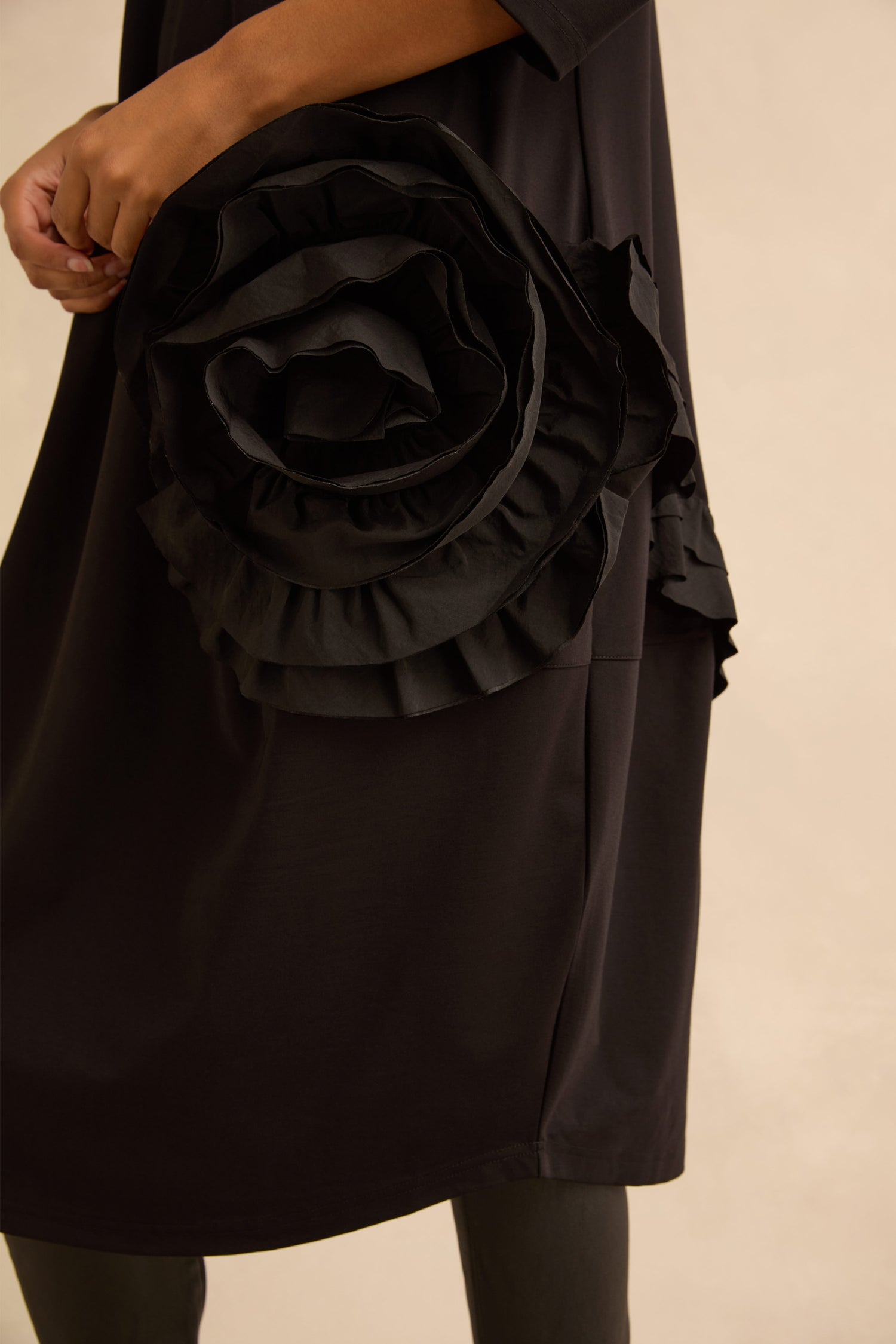 A black Taffeta Flower Detail Jersey Dress featuring a large, ruffled taffeta flower at the hip.