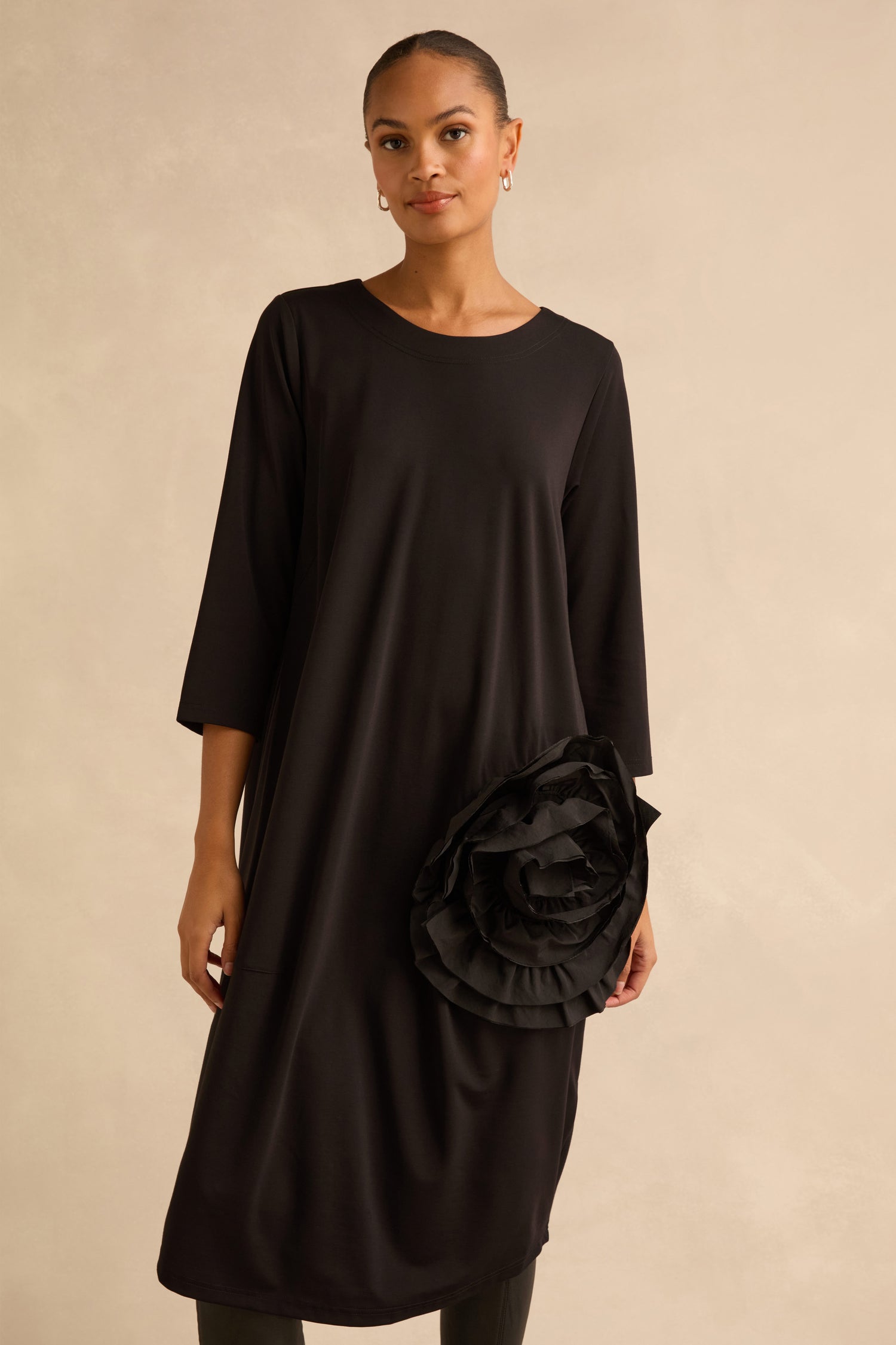 A black, knee-length Taffeta Flower Detail Jersey Dress in a cocoon silhouette with three-quarter sleeves and a large fabric flower detail at the hip.