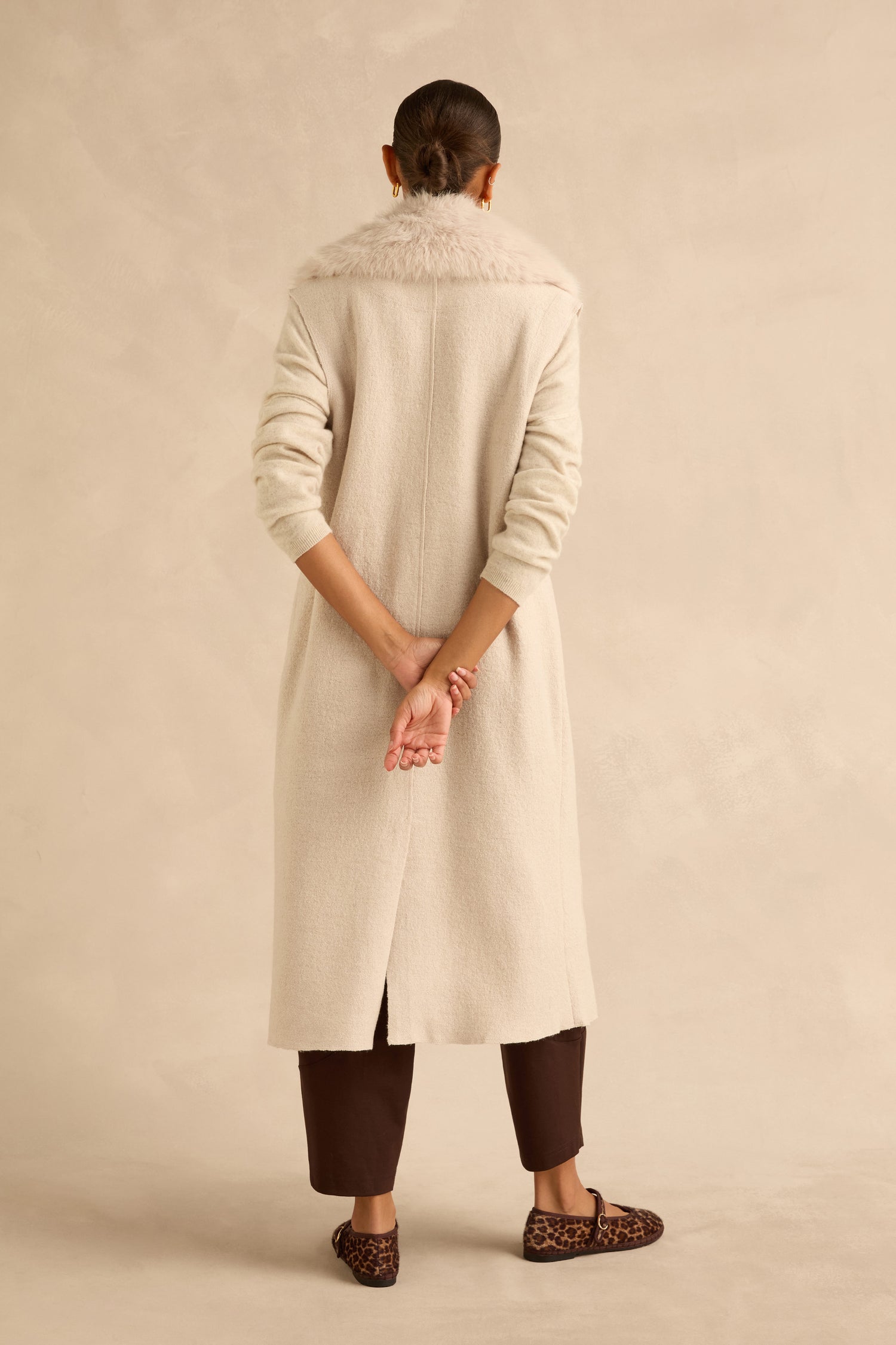 Back view of a person wearing a cream-colored Detachable Fur Long Gilet over dark trousers and leopard-print flats.