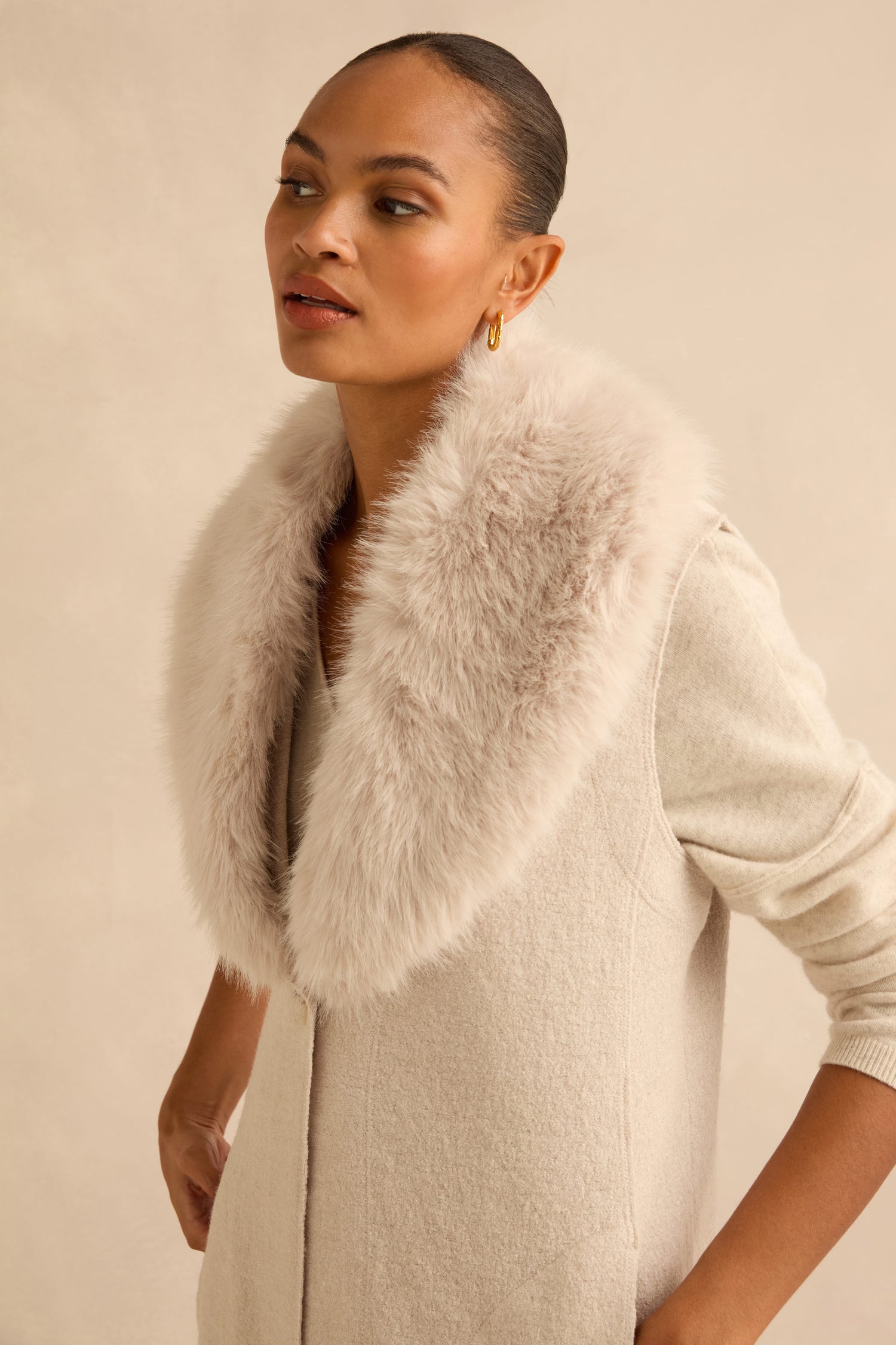 A woman wearing a Detachable Fur Long Gilet made of a wool blend with a large, detachable faux-fur collar.
