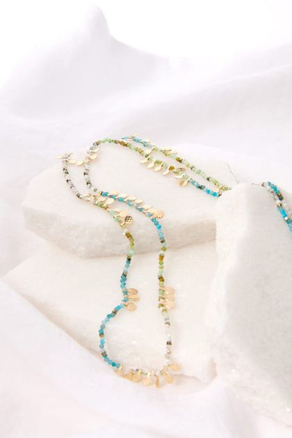 Long Turquoise Bead Necklace displayed on white crystal sugar.