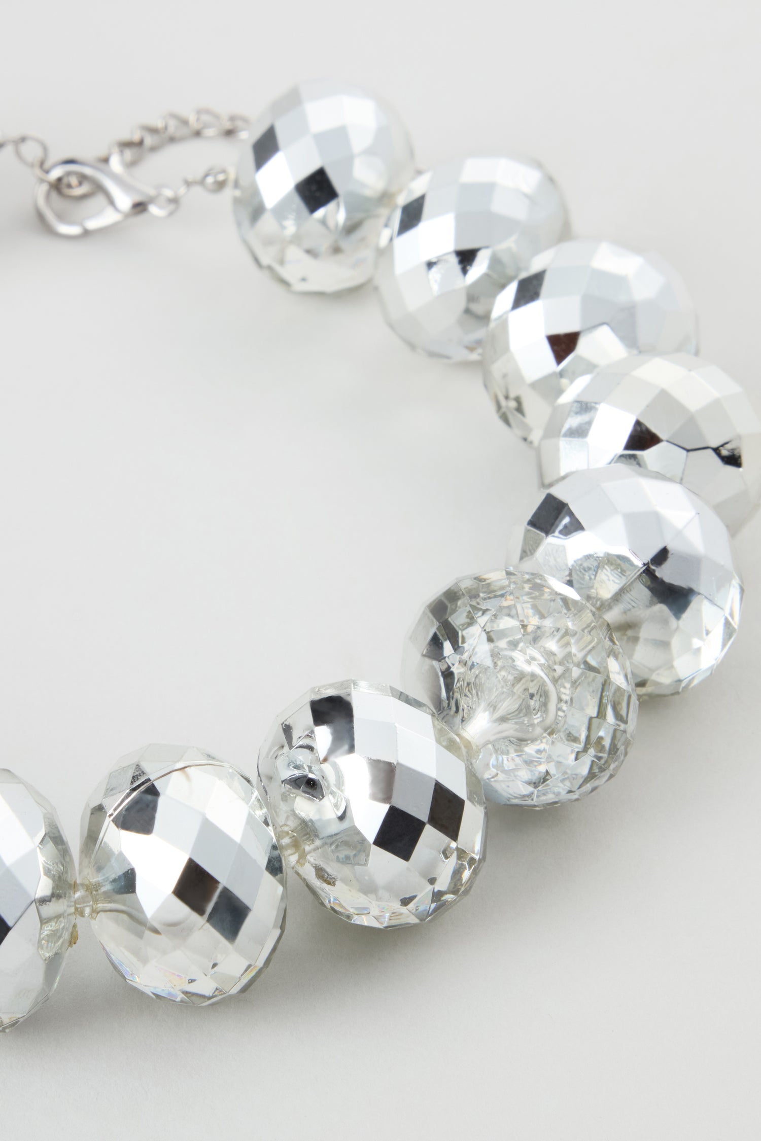 A close-up view of the Silver Disco Necklace, featuring large faceted silver-toned beads and a metal clasp, displayed on a neutral background.