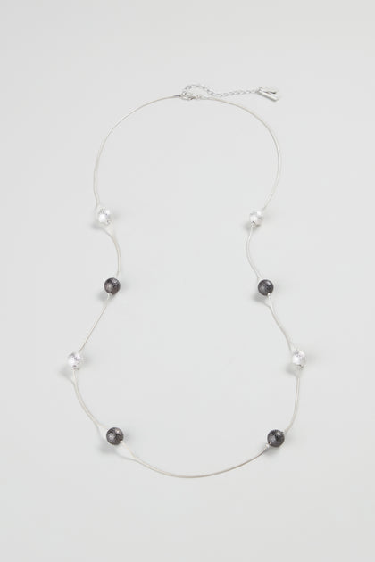 The Sparkle Spheres Necklace showcases alternating black and clear round silver beads, evenly spaced on a thin chain, elegantly presented against a white background.