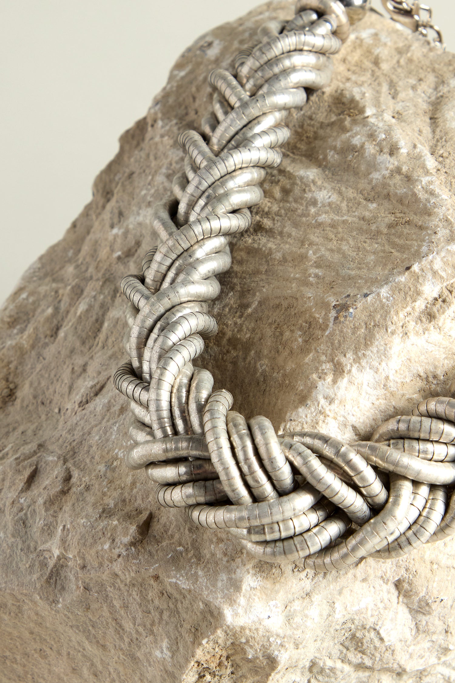 Discover modern sophistication with the Silver Braided Necklace, beautifully showcased against a textured rock backdrop.