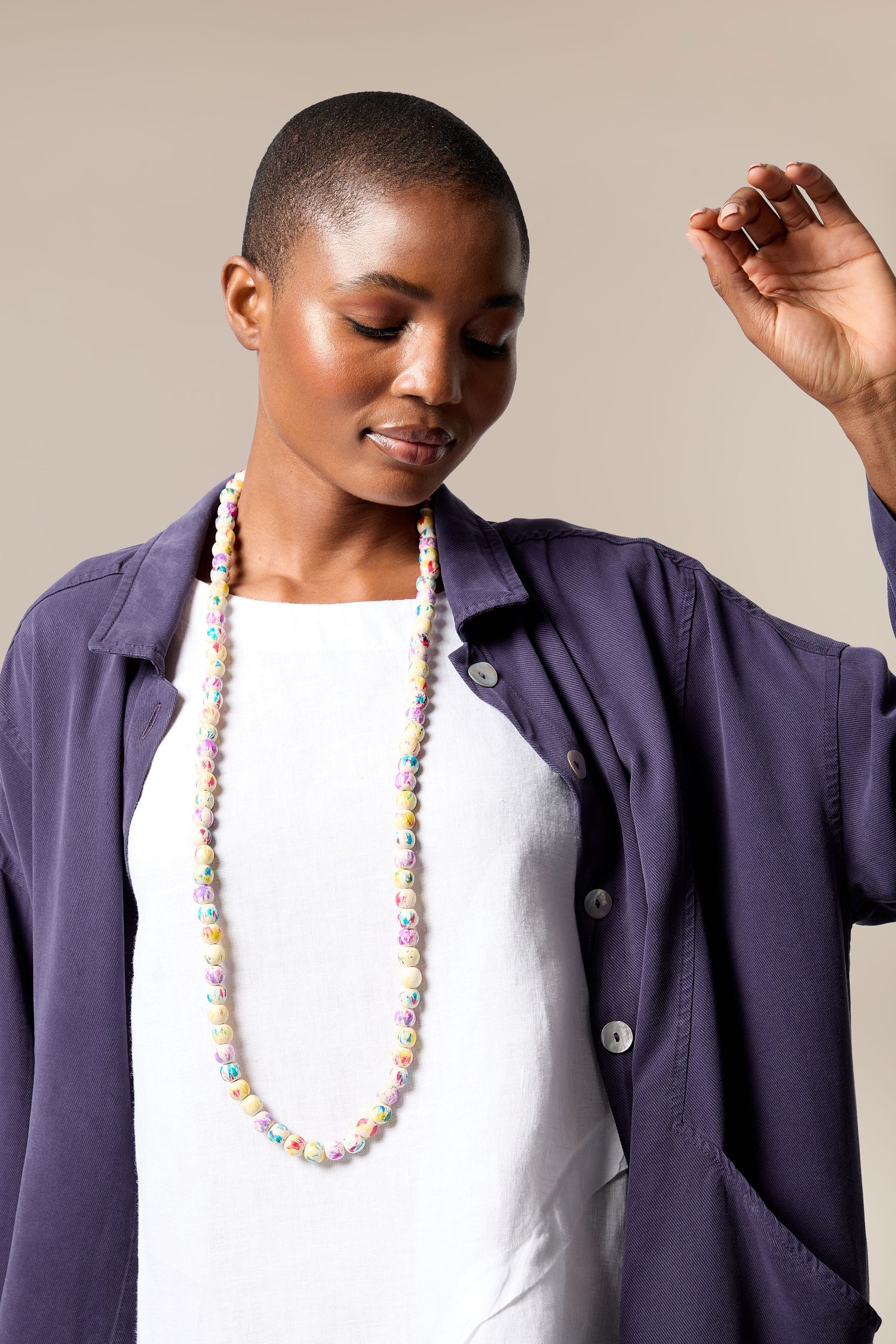 A woman in a purple jacket wearing a Painted Spheres Necklace.