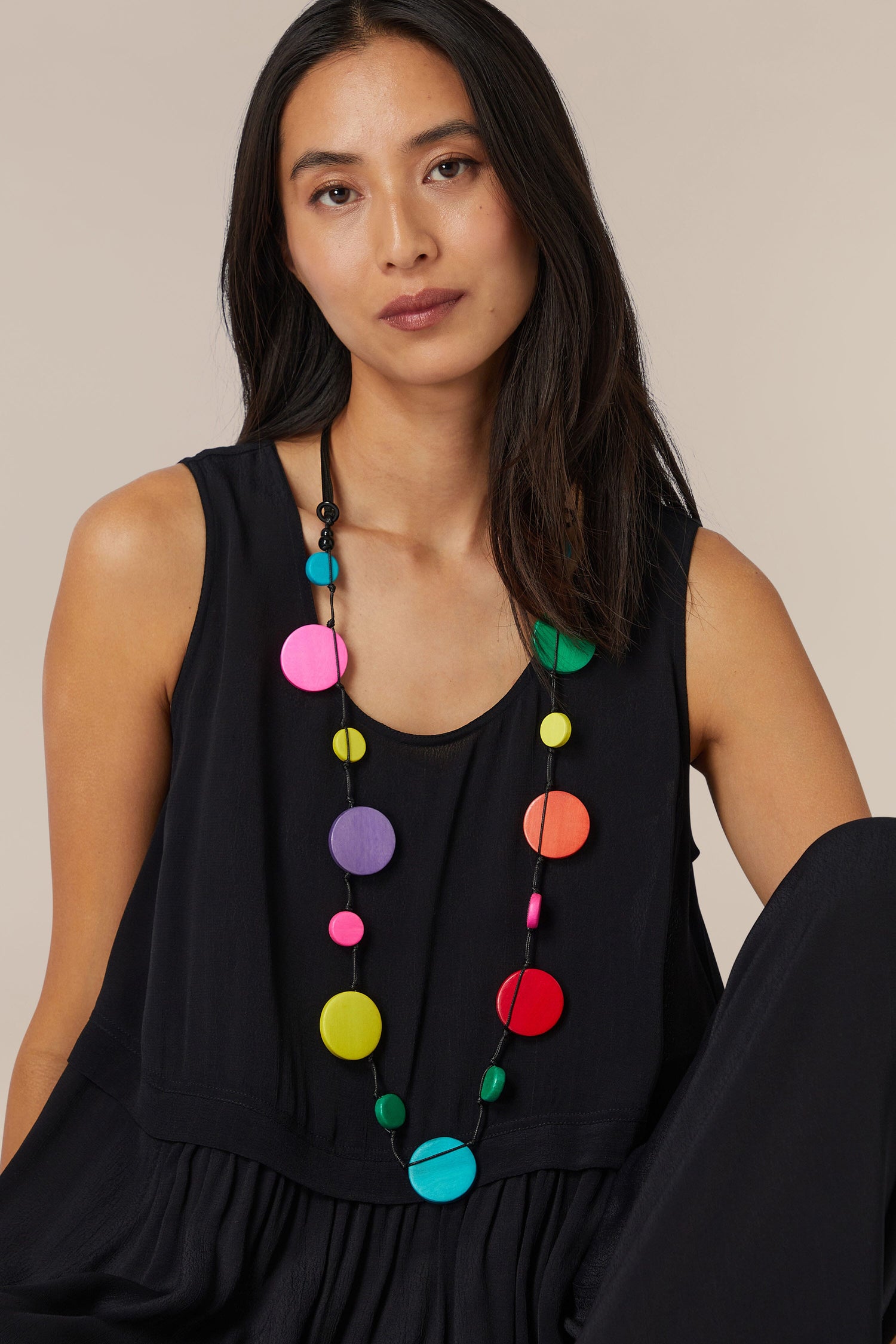 Woman in a black sleeveless top wearing an Rainbow Planets Necklace with colorful wooden discs.