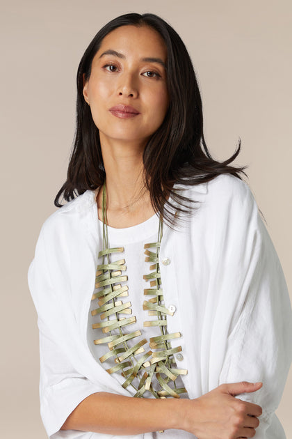 Woman in white blouse wearing a statement Metallic Ribbons Necklace with ribbons of adjustable length.