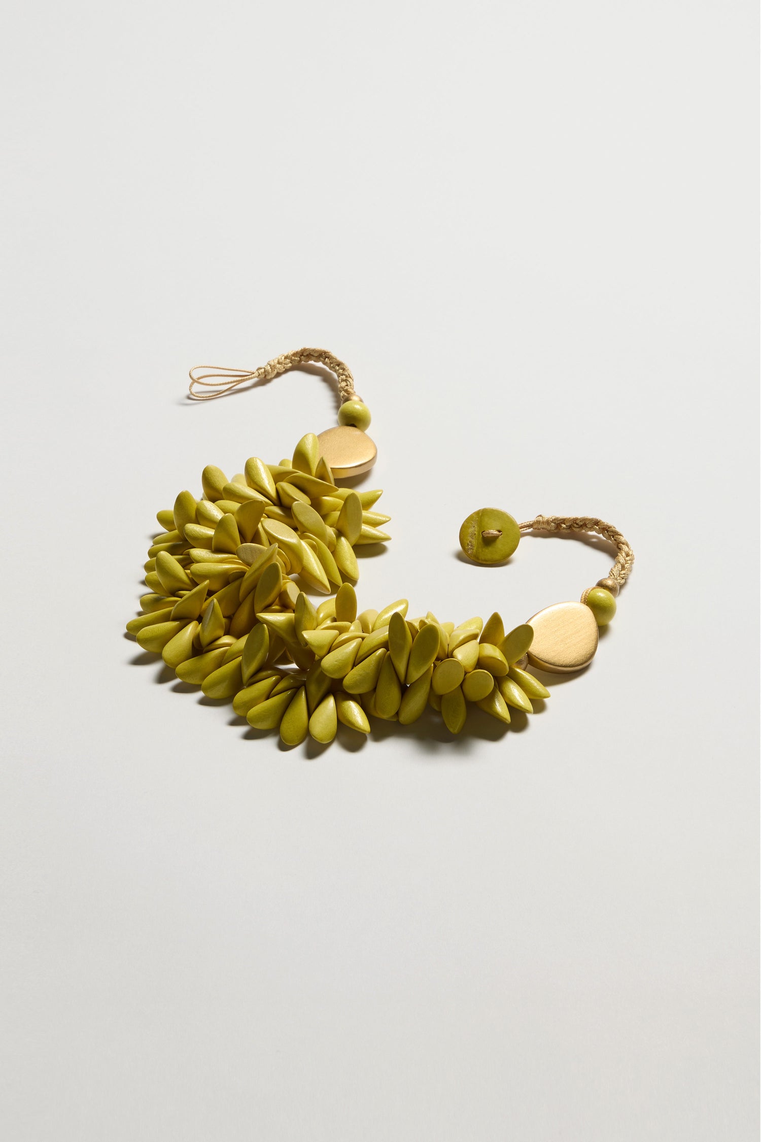 The Citrus Wooden Shapes Necklace is a standout statement piece on a light background, featuring yellow-green beads, an adjustable cord, and round gold accents.