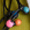 Close-up image of tangled black earphones with colorful earbud covers in pink, blue, and orange, resting on a green fabric background, reminiscent of the Solar System Necklace adorned with multicoloured beads.