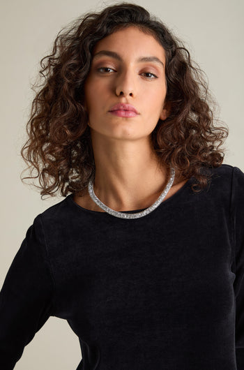 A person with curly hair wearing a black top and the Short Diamante Necklace stands against a plain background, looking at the camera.