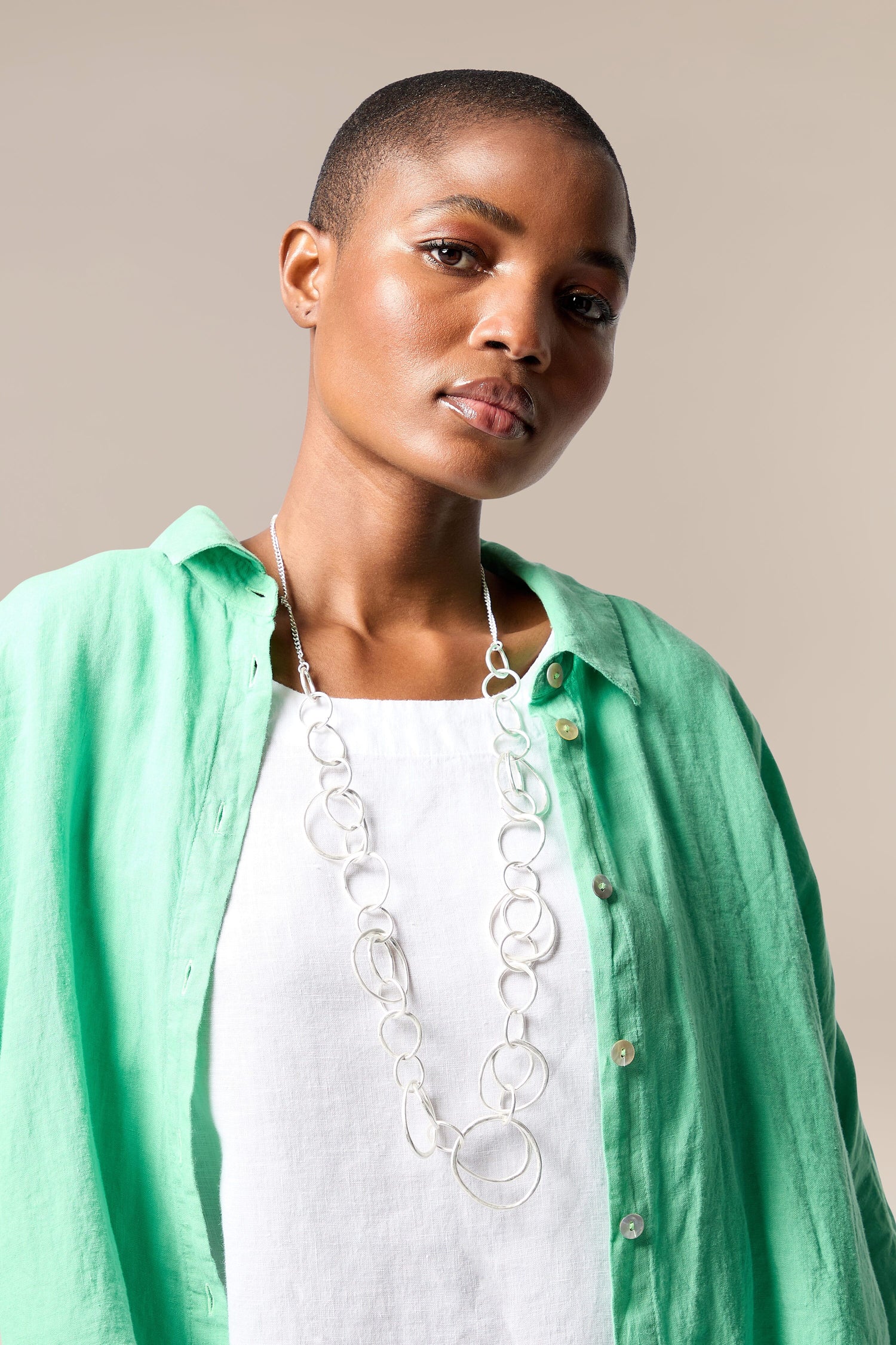 A woman wearing a green shirt and Silver Hoops Necklace with interlocking hoops.