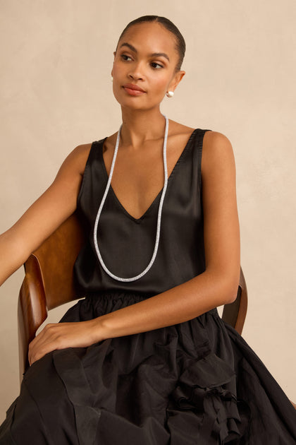 A woman wearing a long, slender Long Silver Diamante Necklace covered in tiny sparkling stones.