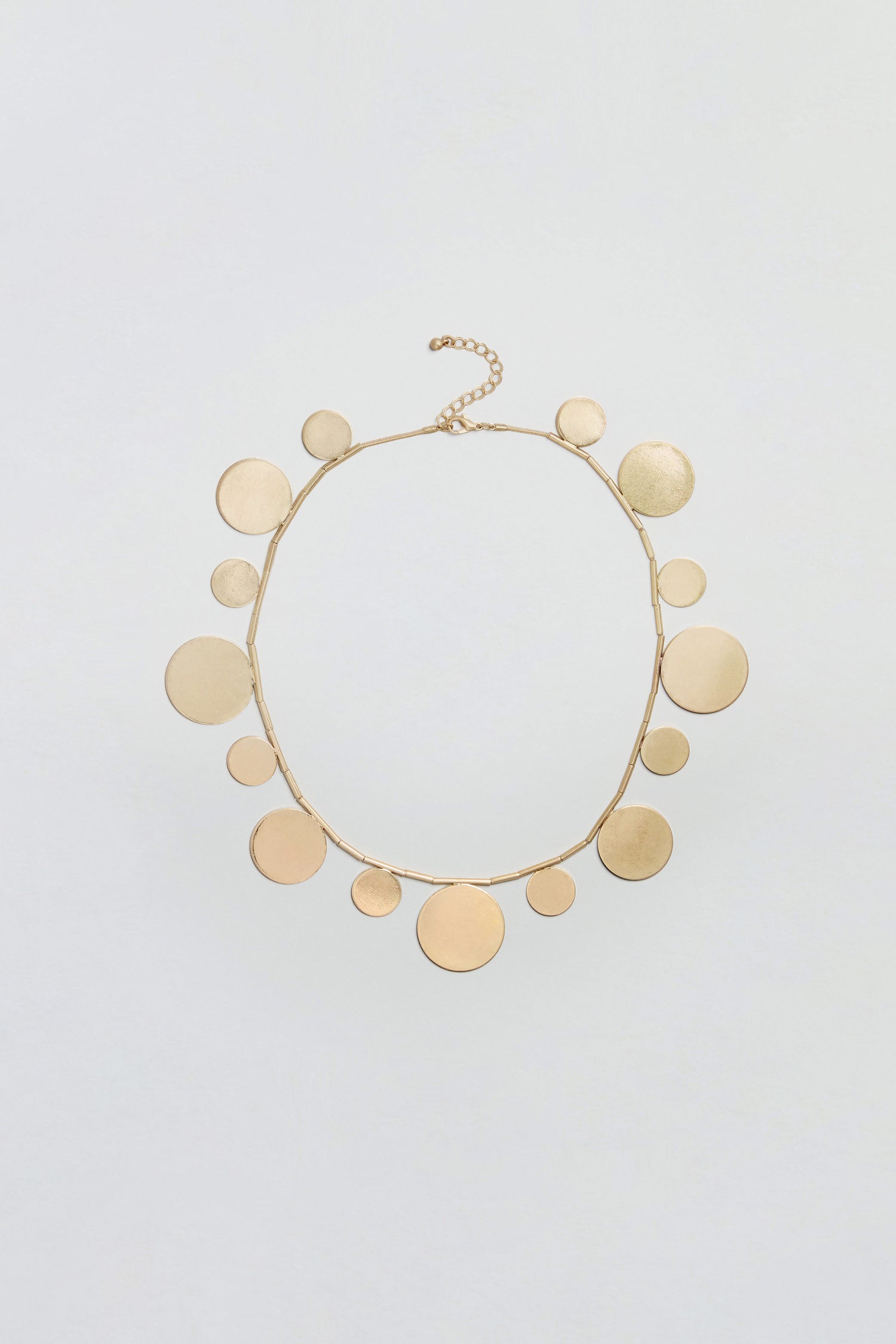 Orbit Disc Necklace featuring multiple flat, round discs of varying sizes evenly spaced along a thin chain, finished with a lobster clasp and adjustable extension at the top.