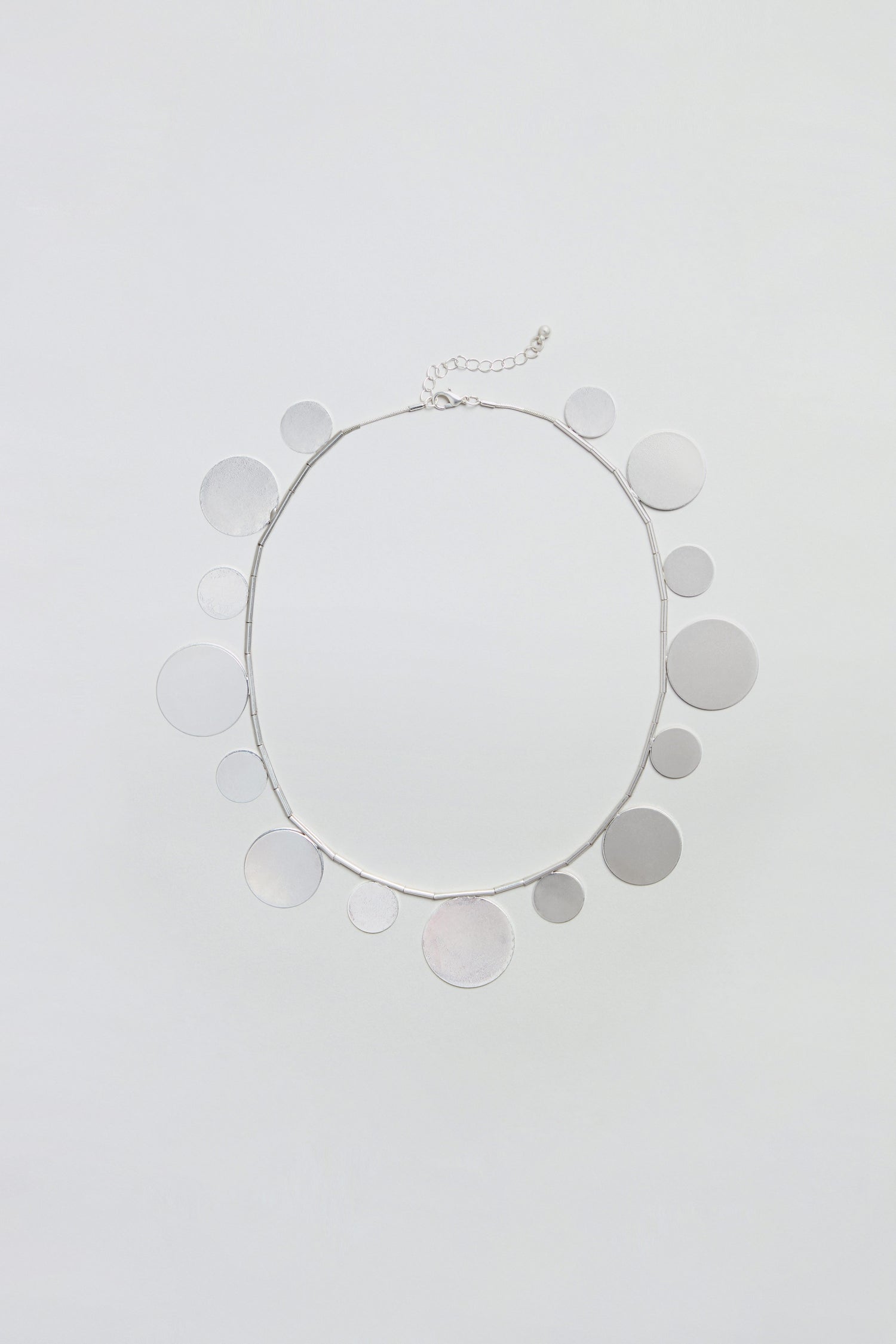 Introducing the Orbit Disc Necklace—a stylish accessory featuring circular silver disc charms evenly spaced along the chain, beautifully presented against a plain white background.