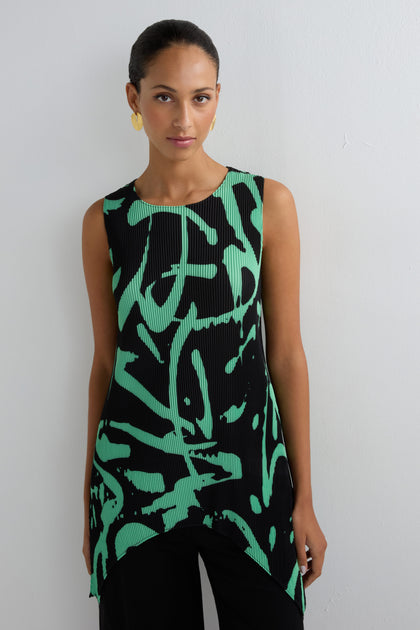 Woman stands against a white wall wearing the Long Print Pleated Vest—a sleeveless black top with green abstract print—paired with black pants and gold earrings, creating a modern wardrobe essential for any season.