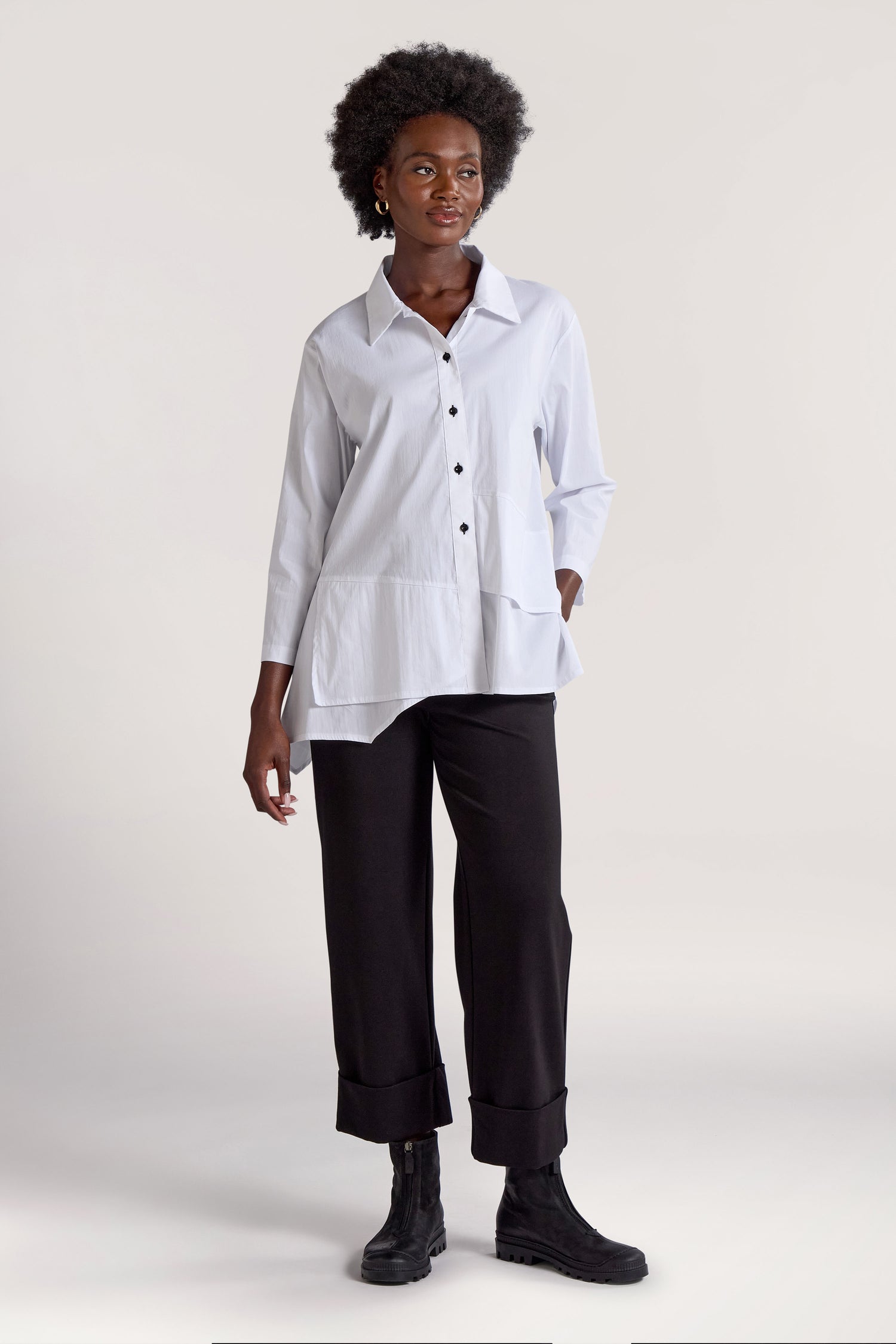 A person wearing a white Panel Hem Shirt, black pants, and black shoes stands against a plain background.