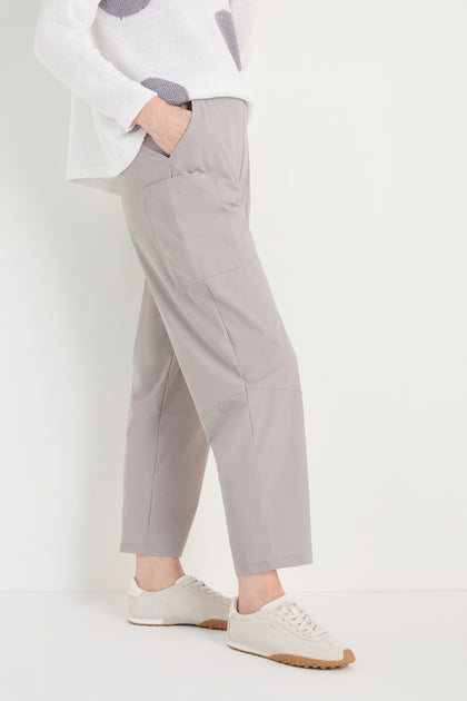 Person wearing light gray Tapered Trousers with a cropped length, a white heart-pattern sweater, and beige sneakers, standing against a plain white background.