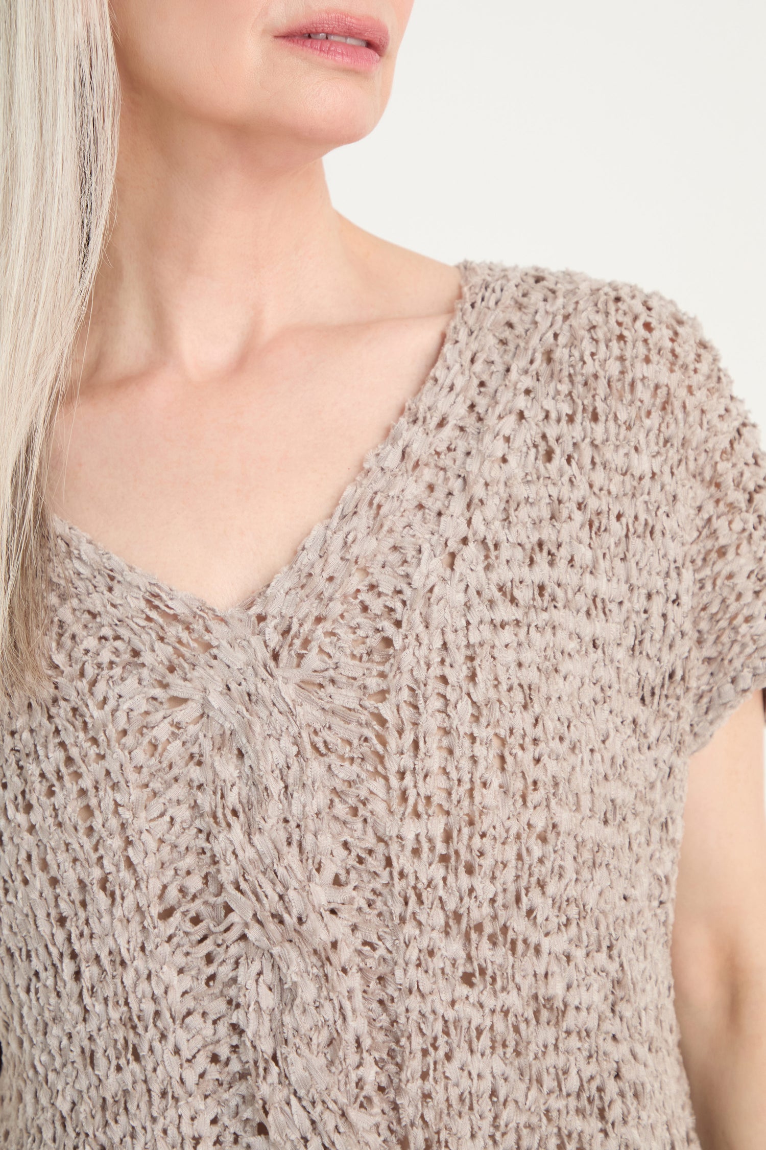 A woman with long, light hair wears the V-Neck Cotton Blend Knit in light brown. The image is cropped from her shoulders to mid-chest.