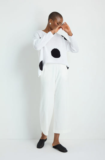 A person stands against a plain white background wearing Wide Leg Pocket Trousers, a sleeveless knitted top, and white sneakers.