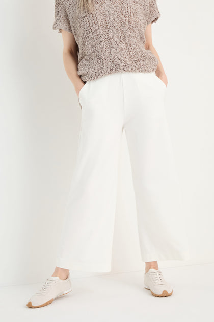 Person wears Wide Leg Pocket Trousers with an elasticated waist and white sneakers, standing against a plain white background with hands in pockets.