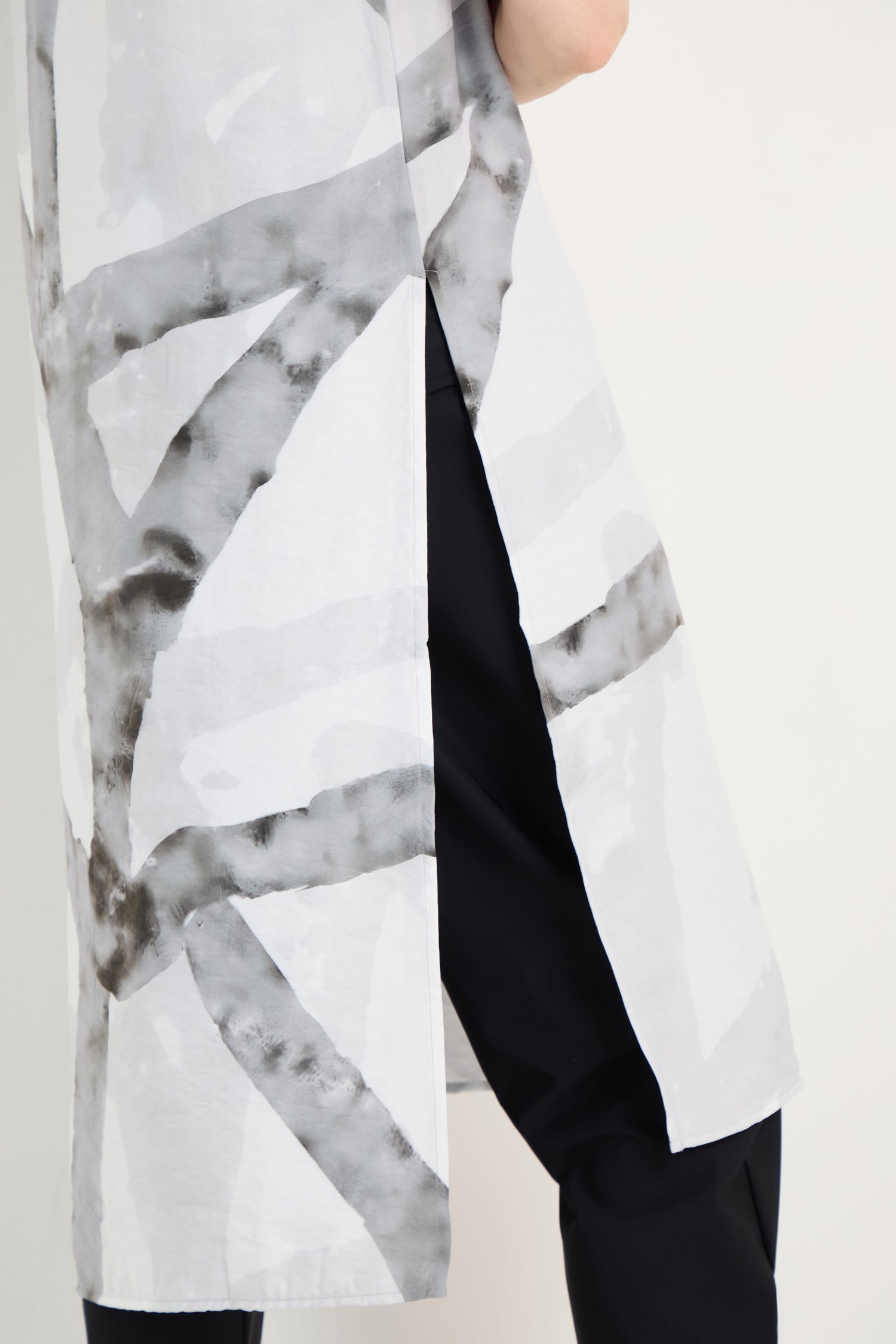 A person wears the Brushstroke Print Long Tunic, featuring abstract black stripes, over black pants, shown from midsection to knee against a plain background.