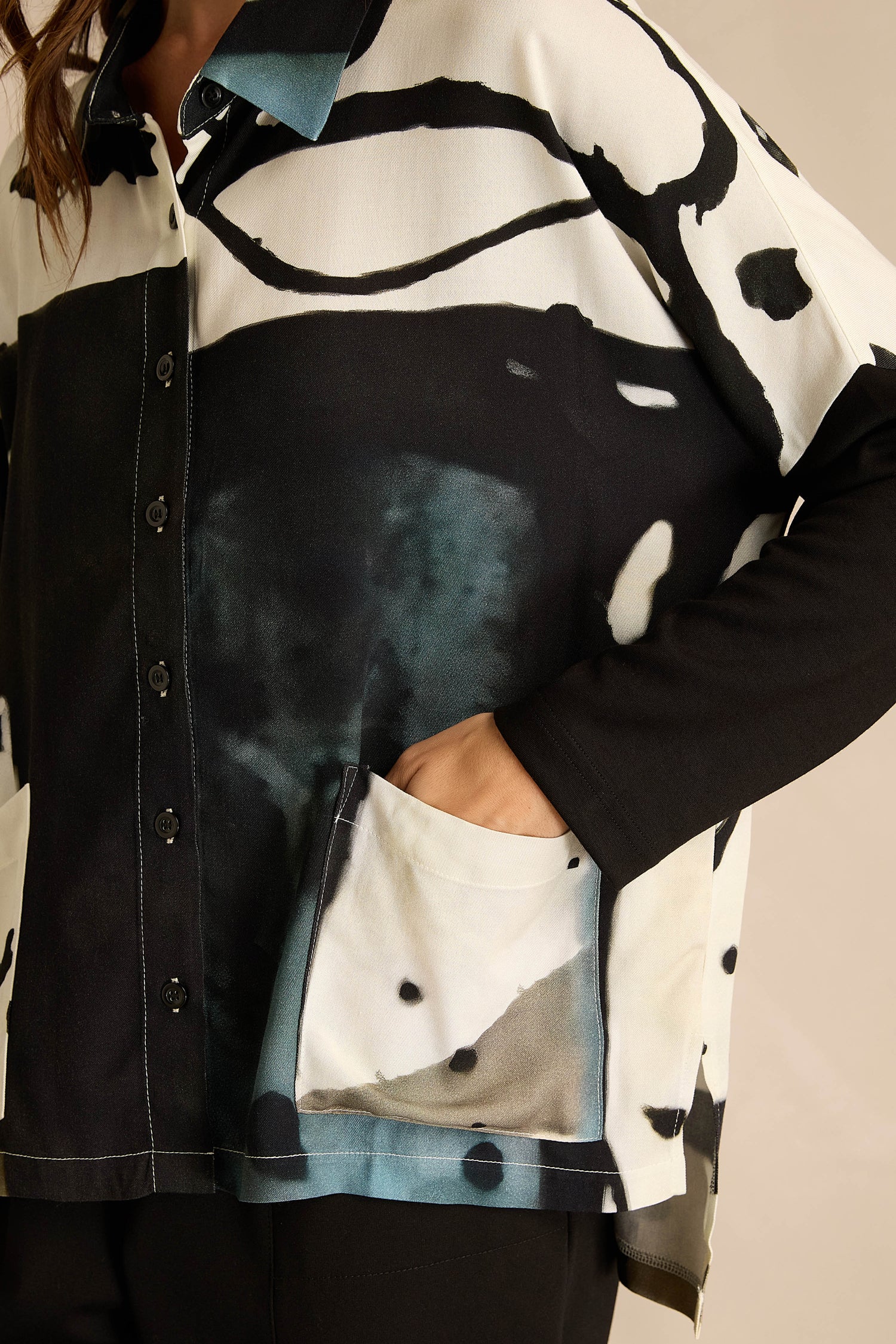 A person is shown from the torso up, wearing the Abstract Watercolour Shirt in black and white, with their right hand placed in a front pocket.
