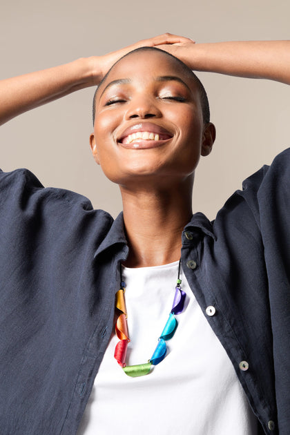 A woman with her hands on her head wearing an Aluminium Rainbow Curl Necklace.