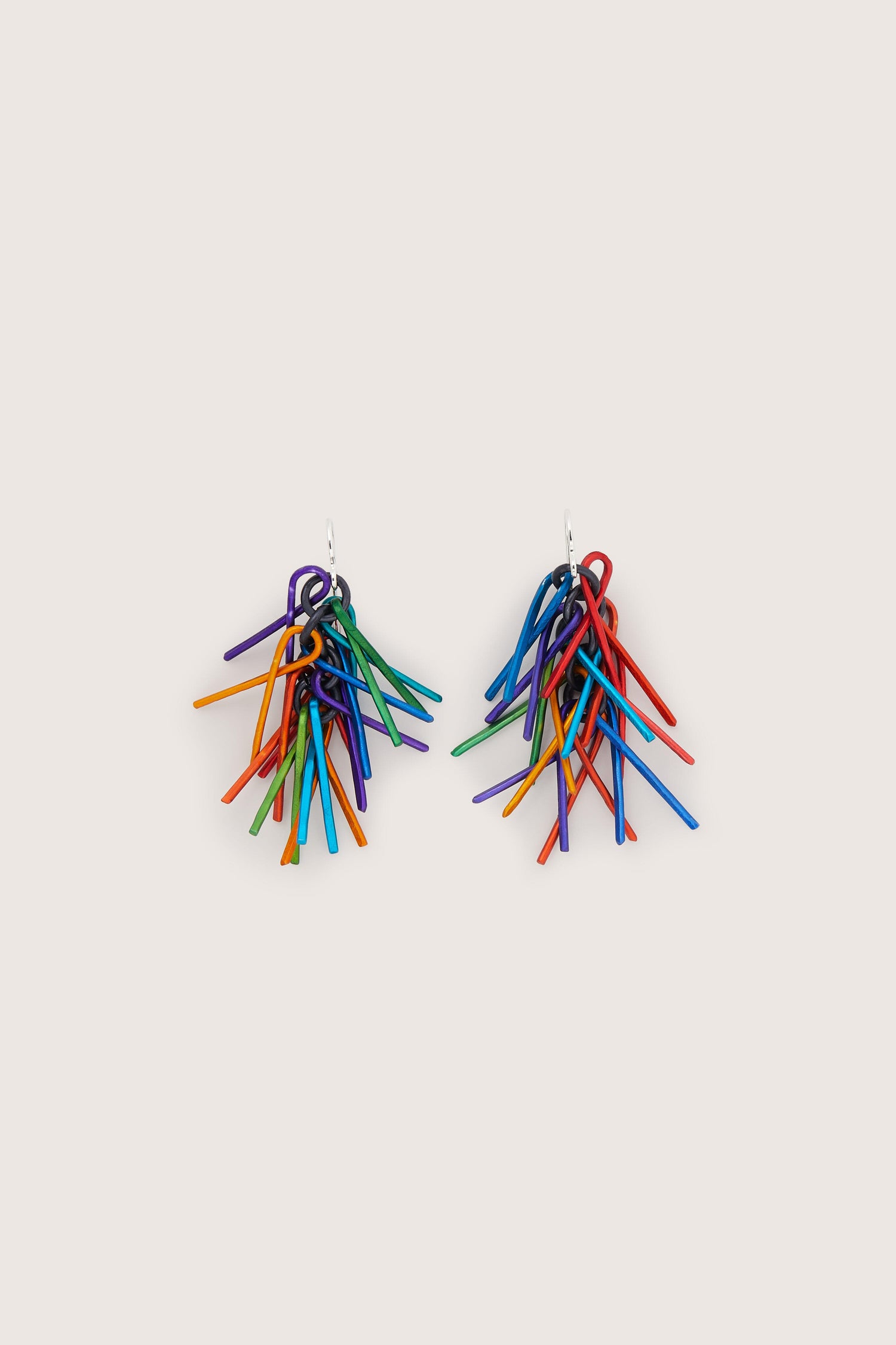 A pair of colorful Fringe Earrings on an aluminium surface.