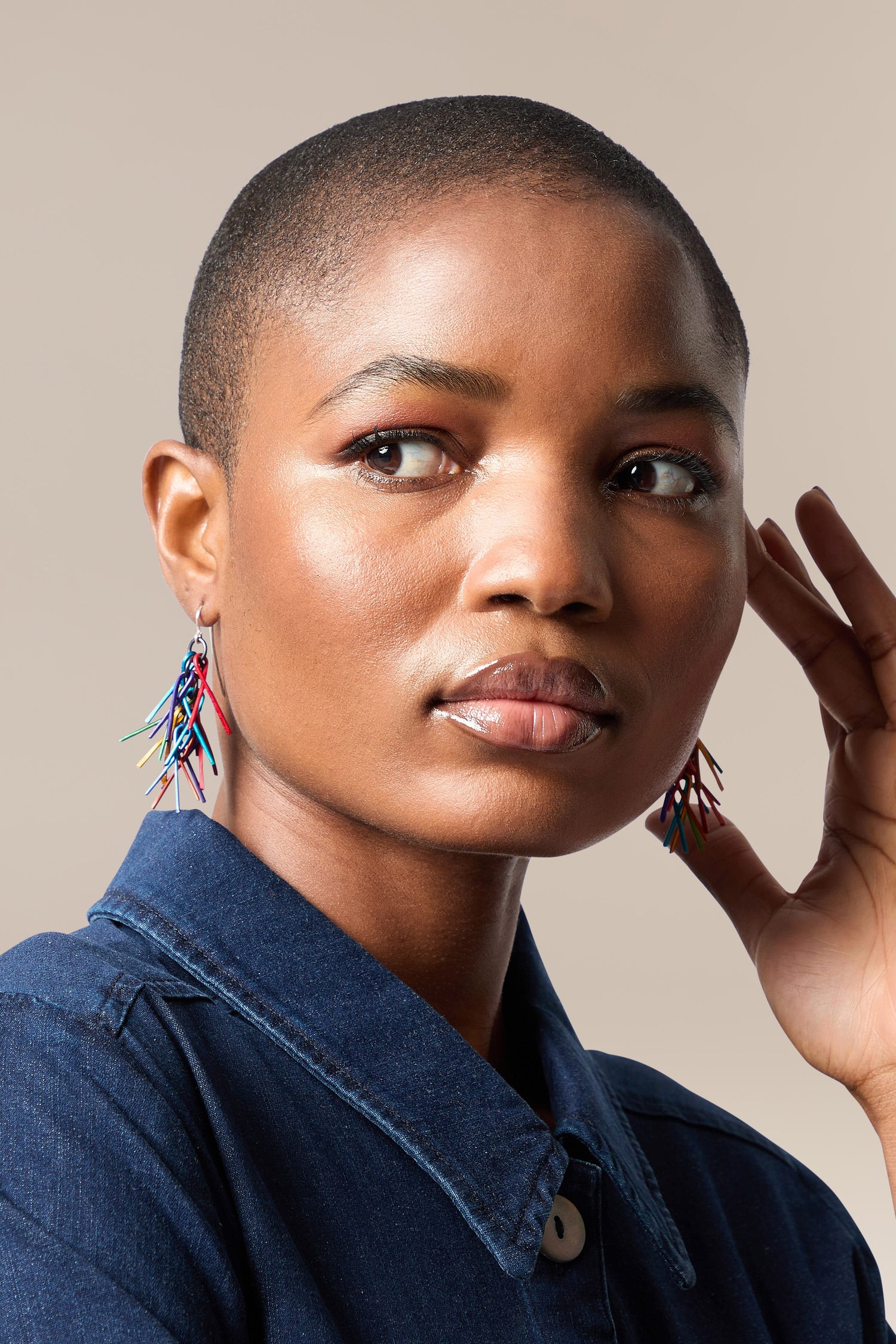 A woman wearing Fringe Earrings and a denim shirt.