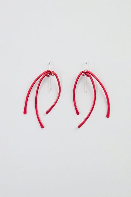 Arc Earrings – Crafted from anodised aluminium, these earrings feature three curved red stems suspended from sterling silver hooks, and are displayed on a plain white background.