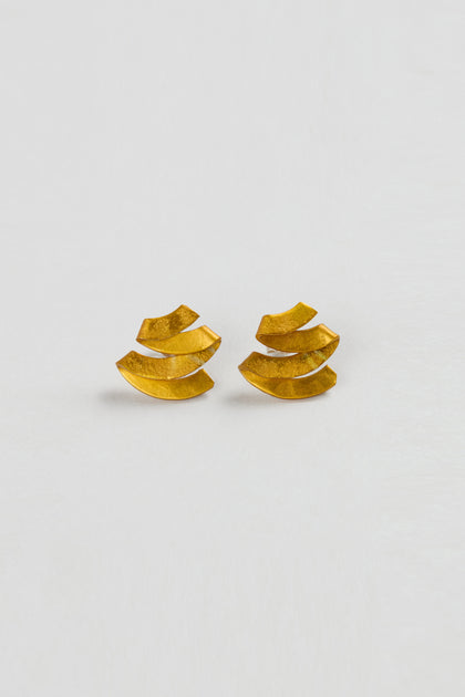 Ribbon Earrings: Gold sculptural earrings featuring a layered, curved design, displayed on a plain white background.
