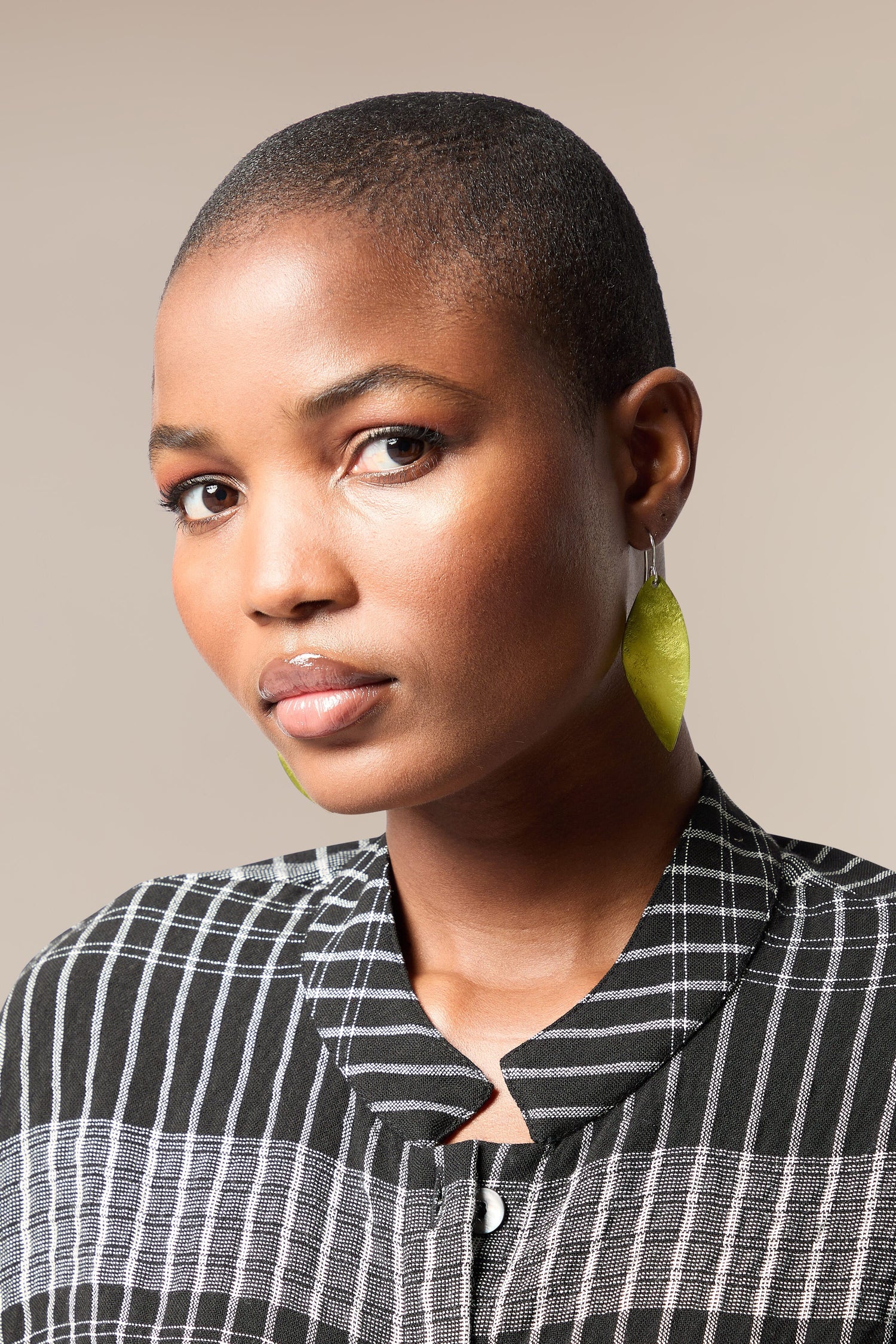 A black woman with a shaved head wearing Leaves Earrings from a Spanish design studio.