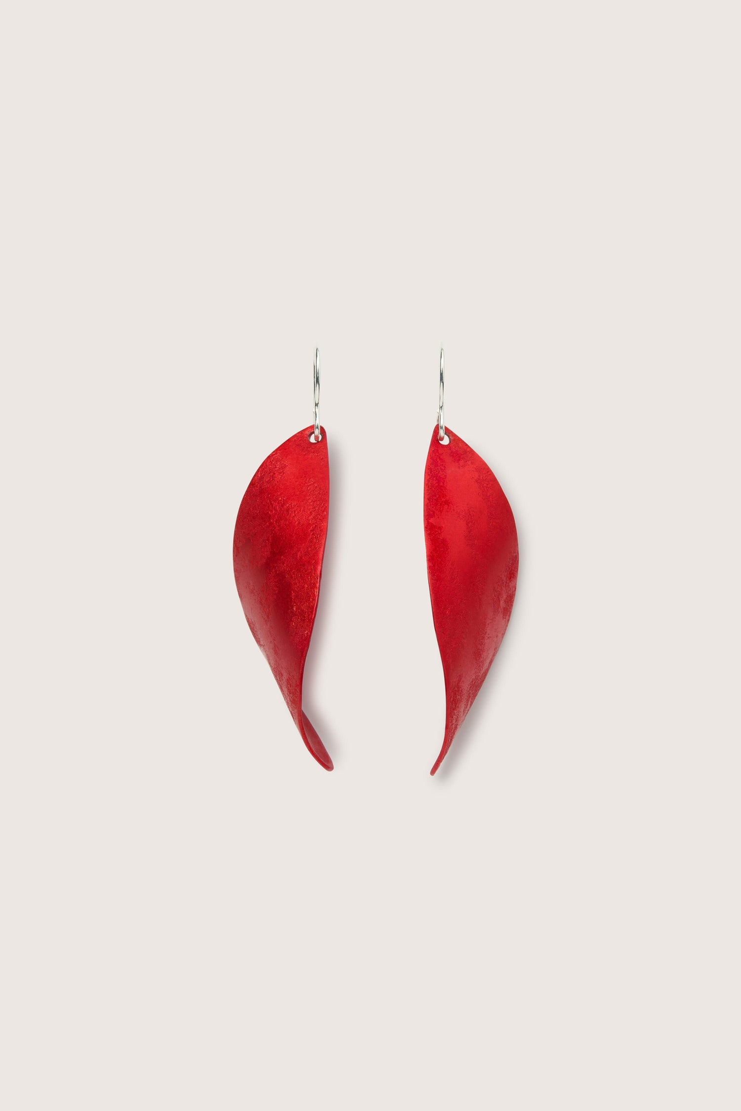 A pair of Leaves Earrings with silver hooks on a white background.
