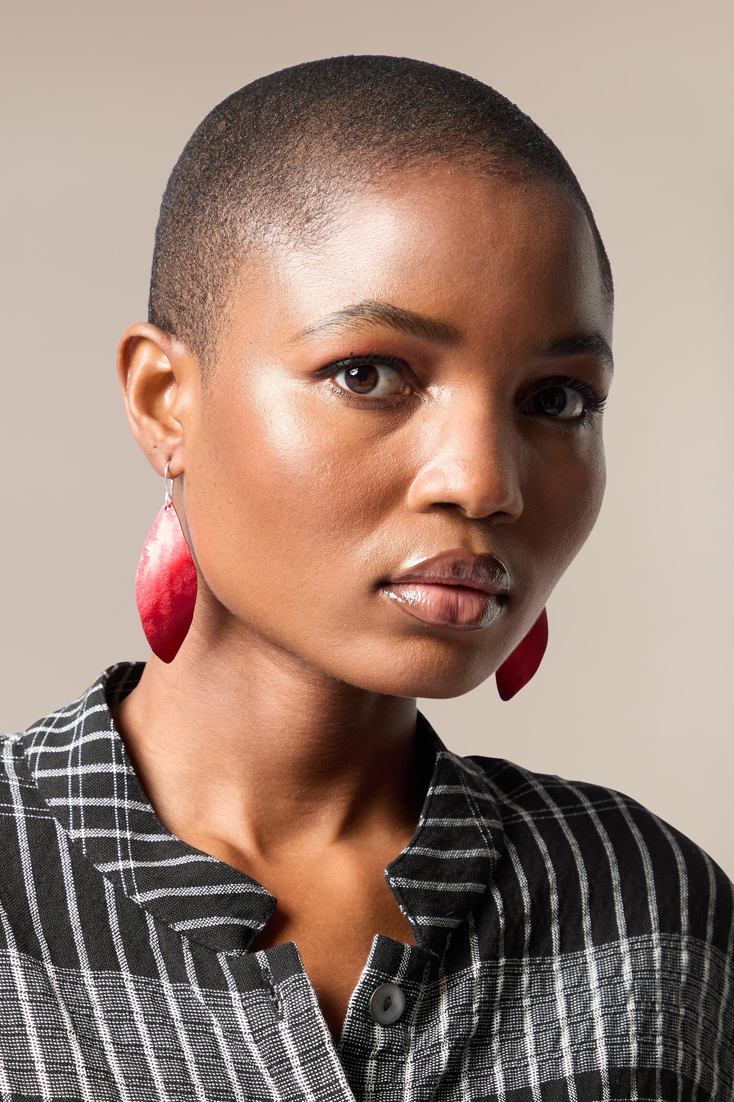 A black woman with a shaved head and silver Leaves Earrings.