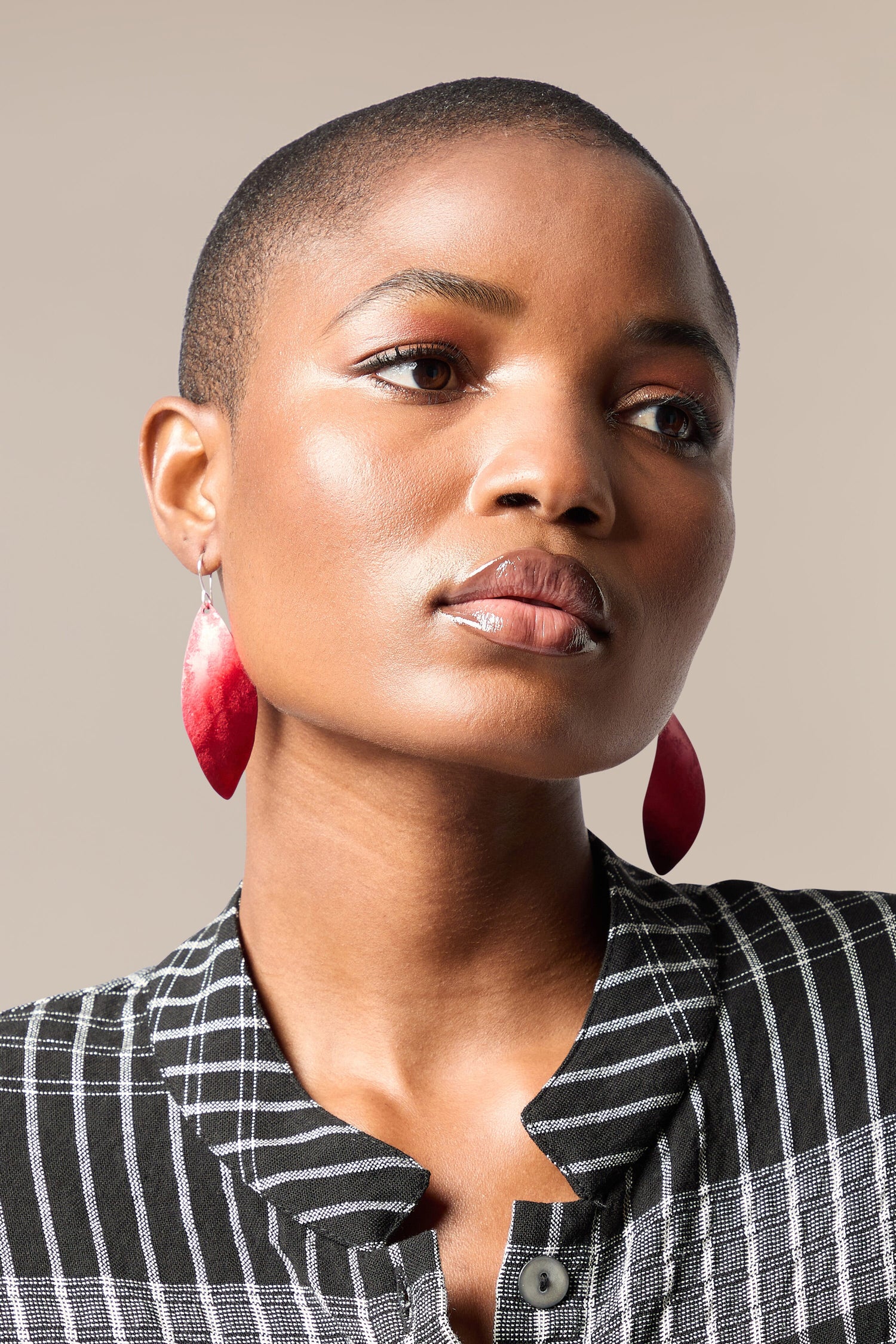 A woman with a shaved head and Leaves Earrings.