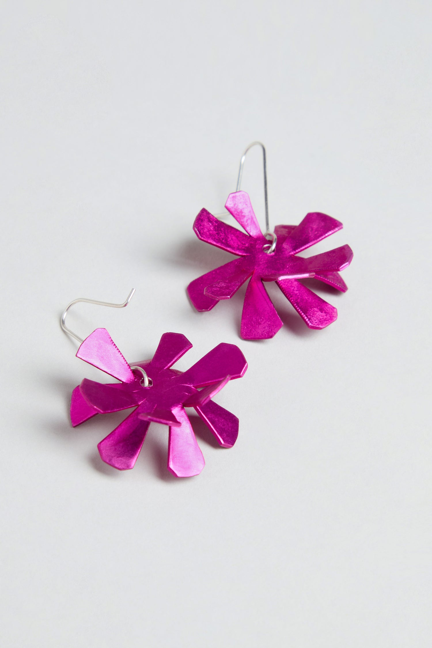 The Flower Earrings feature metallic pink anodised aluminium flowers with sterling silver hooks, showcased against a plain light background.