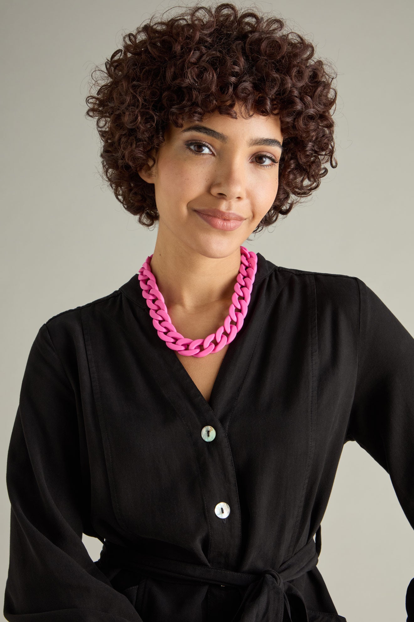 A person with curly hair, wearing a black button-up shirt and the Colour Pop Link Necklace, poses against a neutral background.