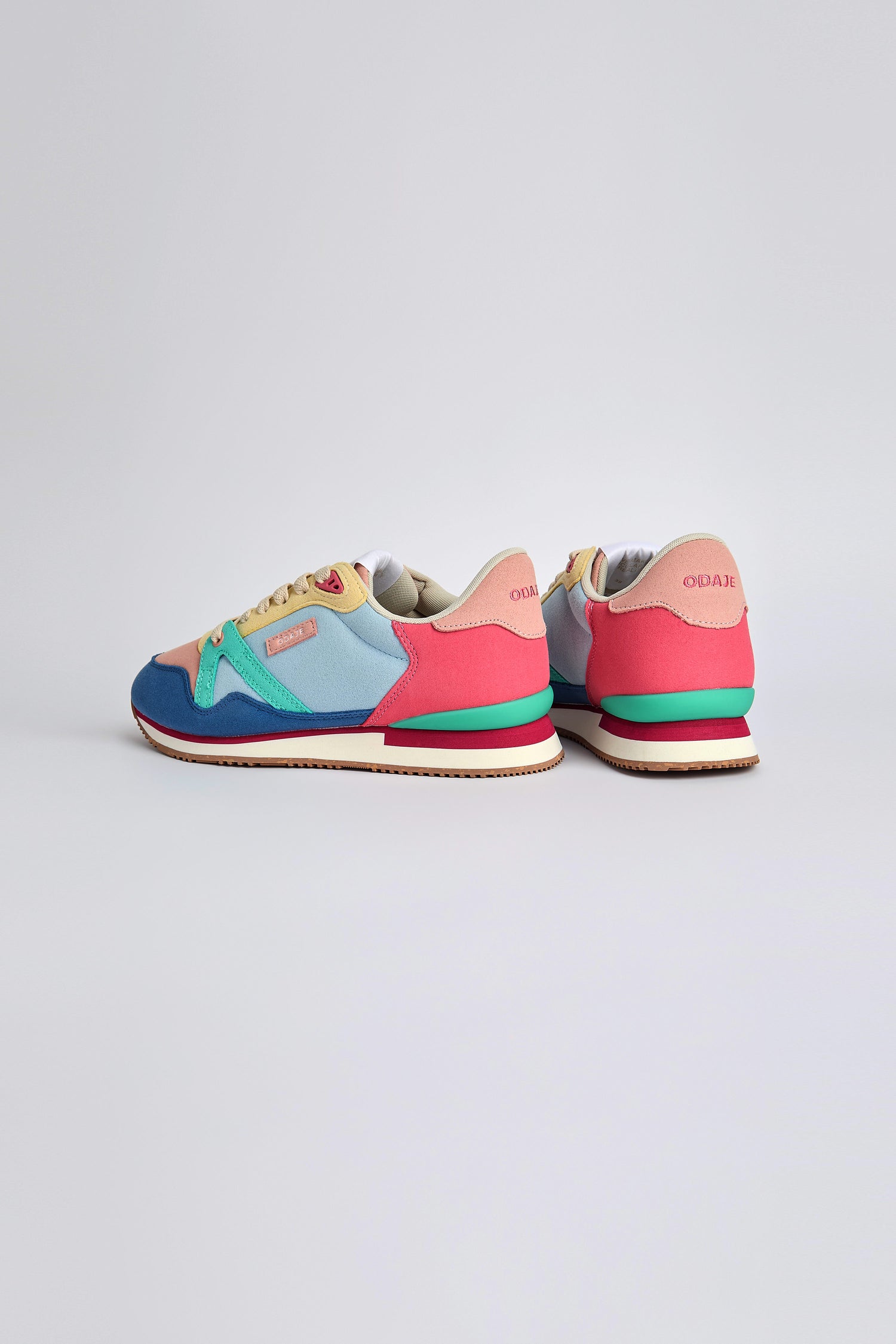 The Andree Trainers, featuring vibrant blue, pink, and green panels made from recycled mesh, pop beautifully against a plain backdrop.