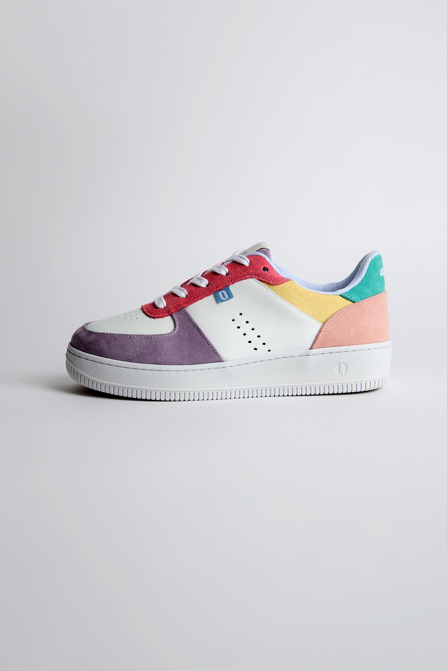 The Maxence Trainers feature a white base with multicolored panels in purple, pink, yellow, and green made from vegan suede for an eco-friendly touch, set against a plain background.