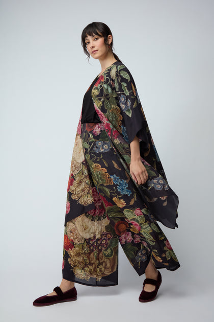 A woman stands sideways against a plain background, wearing the Primula Crepe Throwover with matching wide-leg pants, a black top, and burgundy slippers.