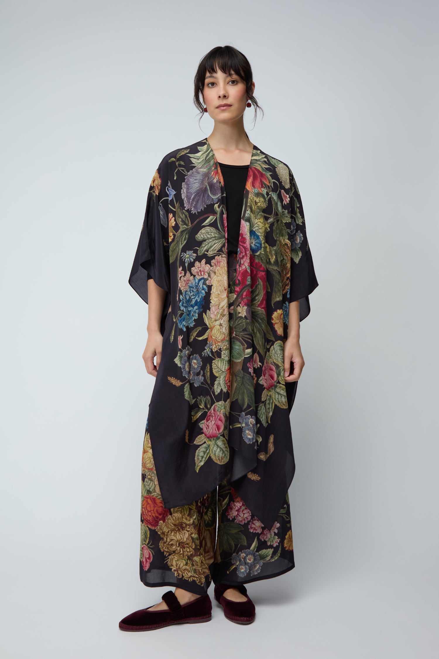A person stands against a plain background wearing the Primula Crepe Throwover with matching wide-leg pants, a black top, and dark slippers.