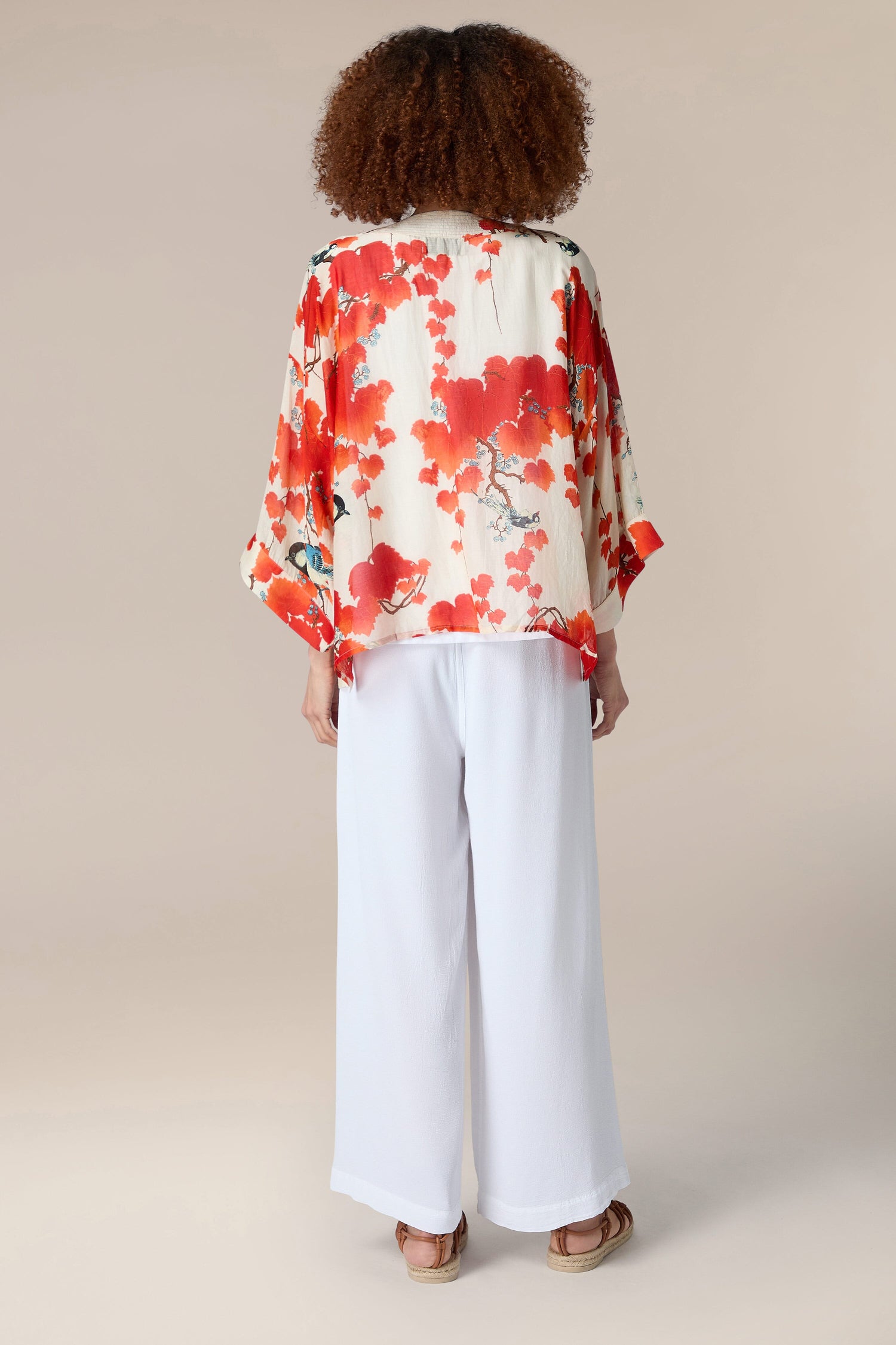 The back view of a woman wearing a red Acer Kimono jacket with an embroidered lapel.