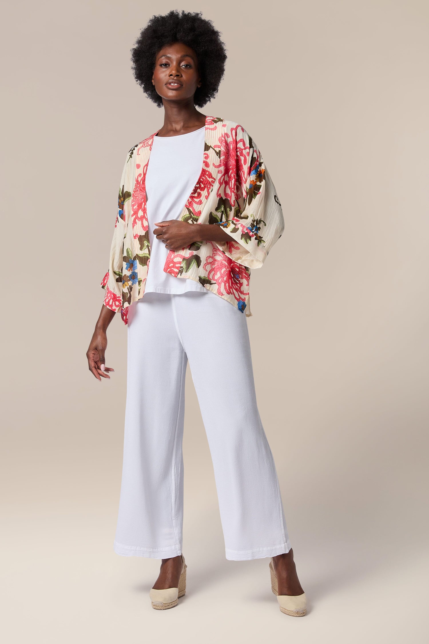 A woman wearing the Chrysanthemum Kimono, a lightweight floral print kimono jacket with an open front and wide leg pants.