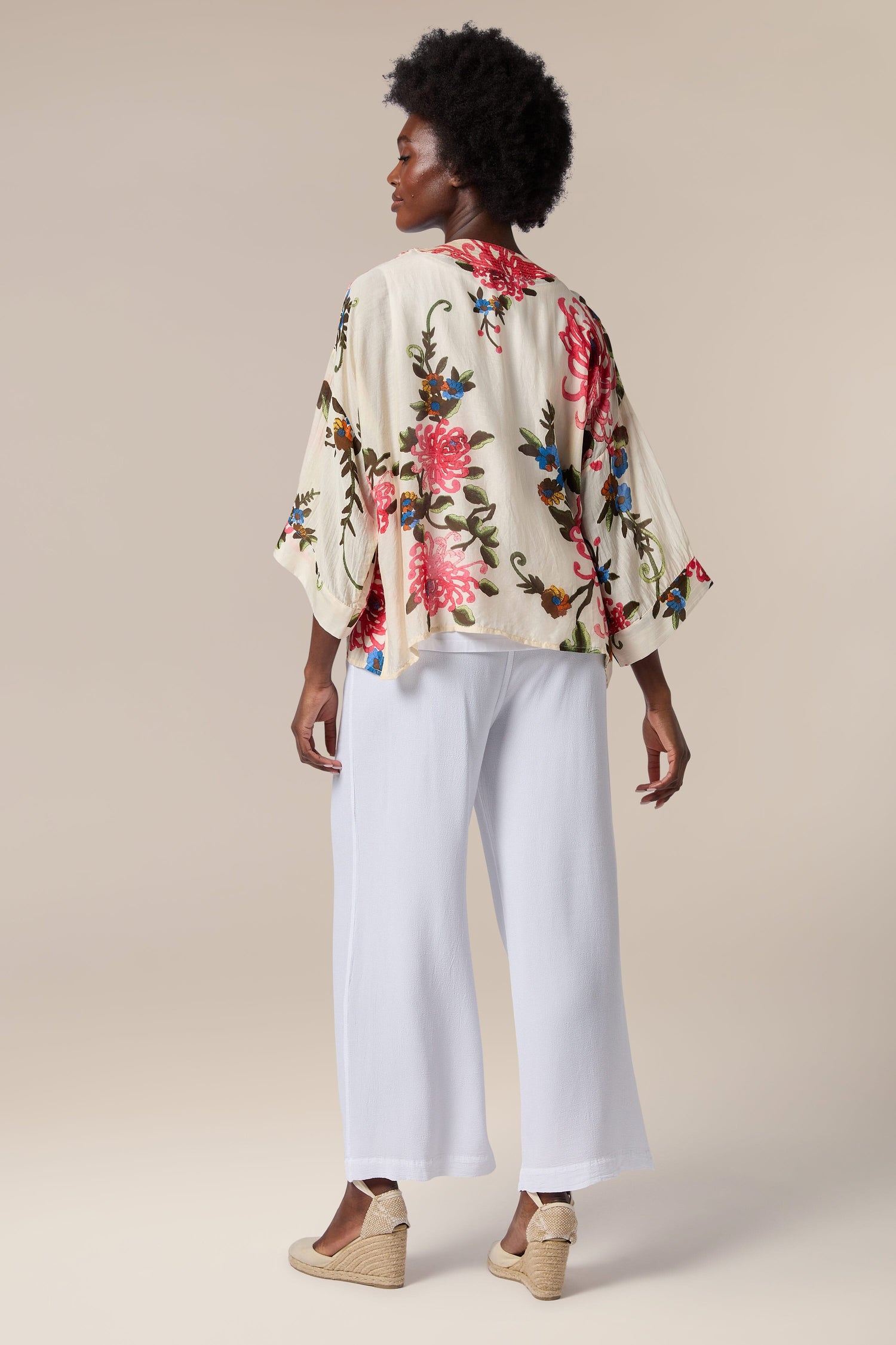 The back view of a woman wearing white wide leg pants and a Chrysanthemum Kimono in lightweight fabric with an open front.