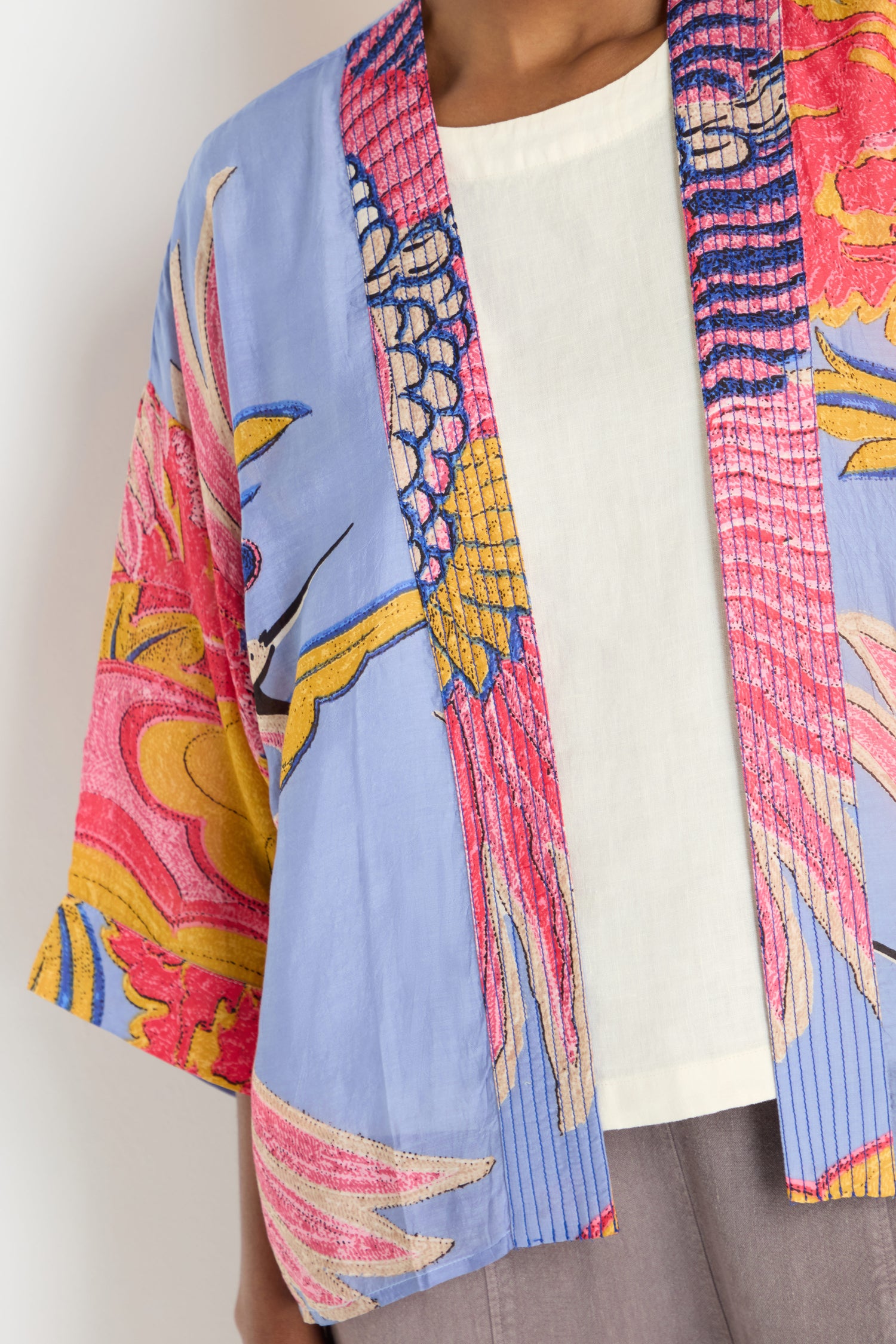 A person wearing the Crane Slate Print Kimono by One Hundred Stars over a white top and grey pants.