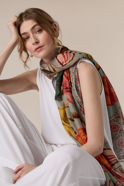 Woman in a white outfit with a Joy Scarf posing with her hand on her head.