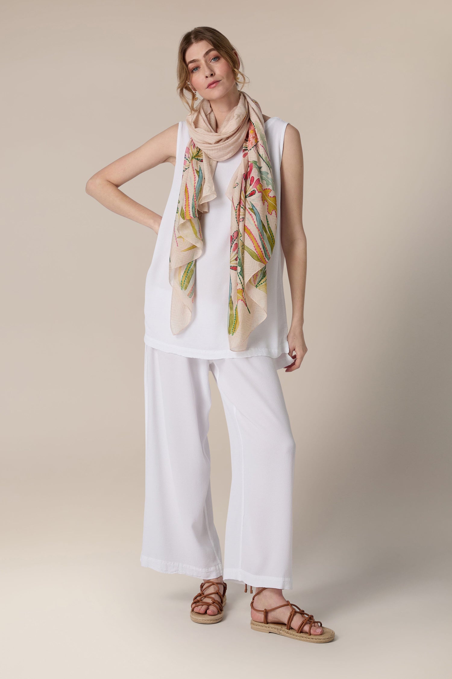 Woman posing in a white outfit with a Pop Flowers Scarf and brown sandals.