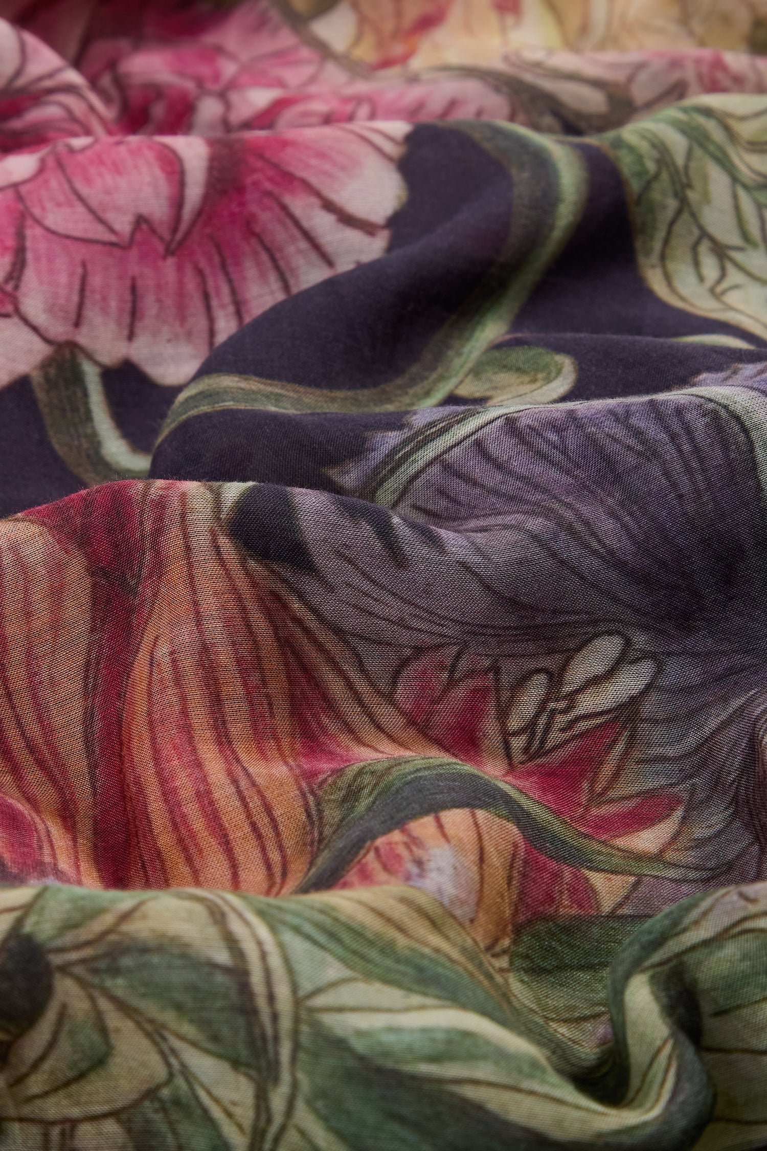 A close-up of the Primula Scarf, showcasing a soft, wavy texture with pink, purple, green, and yellow floral prints—a vibrant accessory essential for elevating any outfit.