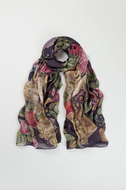 The Primula Scarf, featuring a floral print in shades of purple, green, and pink, is displayed flat on a white background—a stylish accessory to elevate your everyday look.