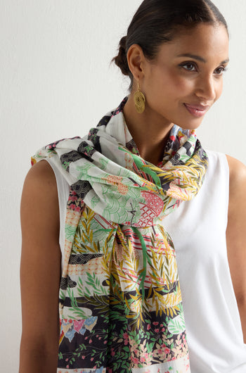 A woman in a white sleeveless top and the Spring Print Scarf showcasing Japanese landscapes, paired with gold earrings, stands against a light background.